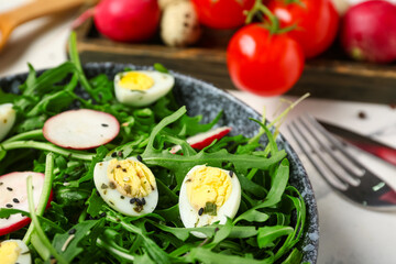 Bowl with tasty arugula salad on marble background, closeup
