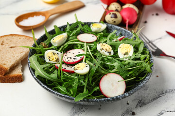 Bowl with tasty arugula salad on marble background, closeup
