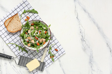 Composition with bowl of tasty arugula salad and ingredients on marble background