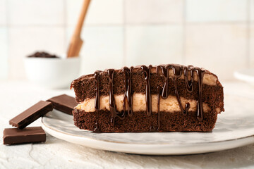 Plate with piece of tasty chocolate cake and pieces of chocolate on white grunge table, closeup