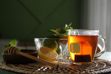 Cup of hot black tea and bowl with honey on black wooden table, closeup