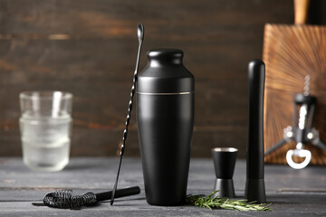 Bartender utensils and rosemary twig on black wooden background, closeup