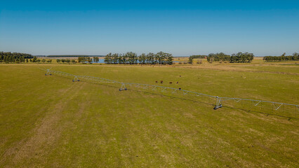 Center pivot irrigation system on agricultural field under clear blue sky.