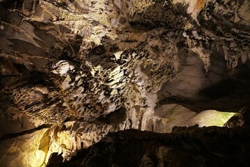 Bright spotlight filters through an opening, illuminating intricate stalactites and stalagmites within Penn's Cave near Centre Hall, Pennsylvania, U.S