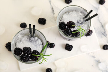 Glasses with tasty cool blackberry lemonade on marble background, closeup