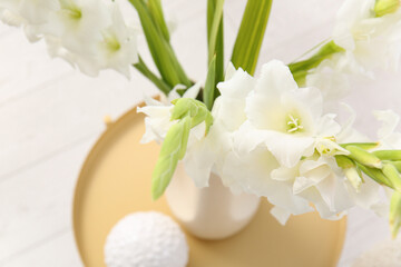 Vase with beautiful white gladiolus flowers on table in living room, closeup
