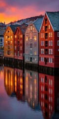 Naklejka premium Colorful waterfront buildings reflect in a calm river at sunset, showcasing a vibrant urban landscape.