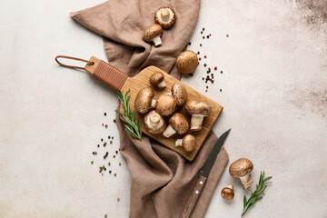 Composition with wooden cutting board, napkin and raw champignon mushrooms on white grunge background, closeup