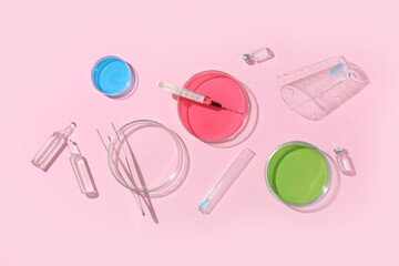 Petri dishes with samples, syringe, laboratory glassware and ampules on pink background