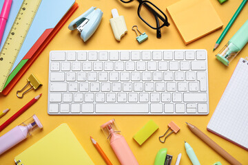 Eyeglasses, computer keyboard and different school supplies on orange background, closeup