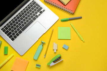 Composition with modern laptop and school supplies on yellow background, closeup