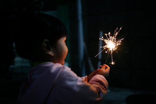 rear view of toddler girl holding sparkler fireworks - Powered by Adobe