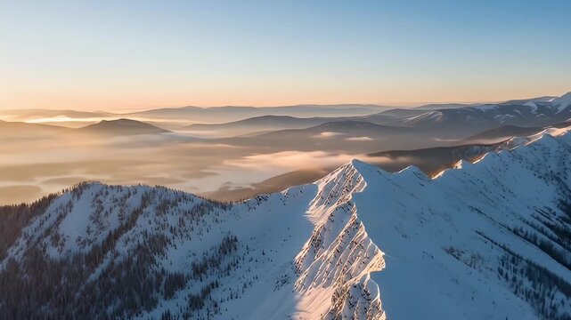 Aerial view of snowy mountain peaks basking in golden light, clouds settle below