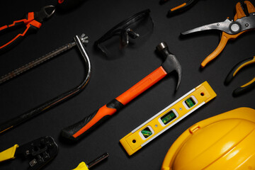 Hardhat and construction tools on black background, top view