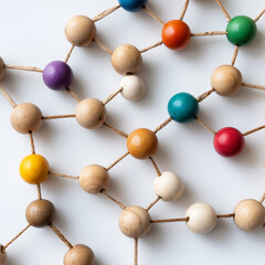 Colorful strings connecting light brown wooden beads on white background, abstract design representing network connections, collaboration, communication, innovation 