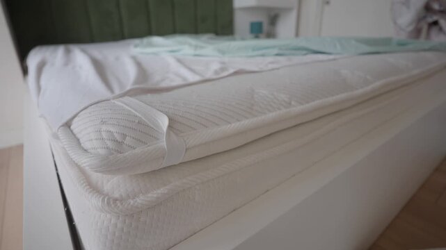 making a bed with a mattress topper and fresh sheets