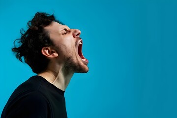 Side view, profile photo of a man shouting with his mouth wide open, isolated on a blue background. Concept with copy space.