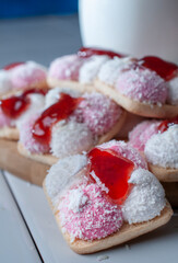 Marshmallow cookies with coconut flakes and strawberry jam on top with a glass of cold milk on the side, foods high in sugar and carbohydrates, macro photography vertical
