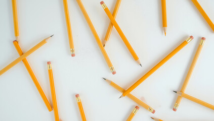 Scattered Yellow Pencils on a White Surface