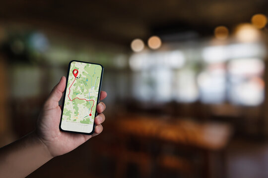 Hand holding smartphone with GPS navigation map and route to cafe destination, concept of mobile app, location search, travel guide, restaurant finding, and digital navigation technology. - Powered by Adobe