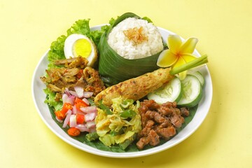 Nasi Campur Bali is a traditional Balinese dish consisting of warm white rice and various side dishes in small portions, such as shredded chicken, sate lilit, lawar, and sambal matah.