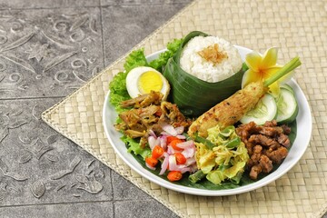 Nasi Campur Bali is a traditional Balinese dish consisting of warm white rice and various side dishes in small portions, such as shredded chicken, sate lilit, lawar, and sambal matah.