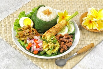 Nasi Campur Bali is a traditional Balinese dish consisting of warm white rice and various side dishes in small portions, such as shredded chicken, sate lilit, lawar, and sambal matah.