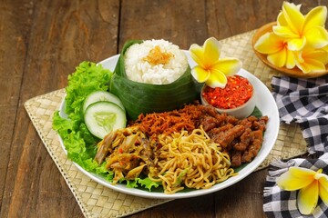 Nasi jinggo is a typical Balinese dish consisting of small portions of white rice wrapped in banana leaves, usually accompanied by side dishes such as shredded chicken, fried noodles, serundeng and ch