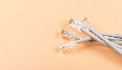 Gray Ethernet cables with clear connectors on a soft peach background for technology and networking concepts