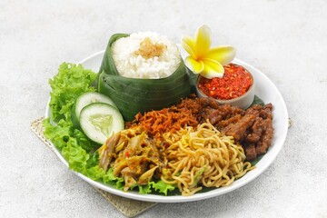 Nasi jinggo is a typical Balinese dish consisting of small portions of white rice wrapped in banana leaves, usually accompanied by side dishes such as shredded chicken, fried noodles, serundeng and ch