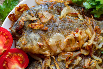 Close-up of fried crucian carp fish with onions. Fresh fried fish with vegetables