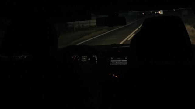 View of a nighttime car journey with dimly lit dashboard and empty road ahead, creating an atmosphere of intimacy, travel, and solitude.