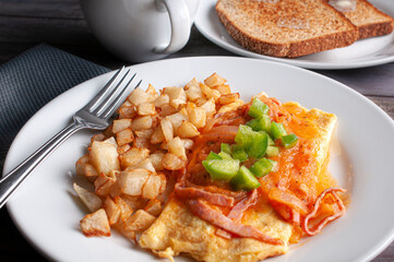 Breakfast with egg, French fries, ham, and tomato sauce on a rustic wooden table with a fork and a white cup and toast with butter angle view