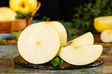 Fresh Yellow Apples from Liaoning China Sliced on Rustic Wooden Board with Mint Garnish