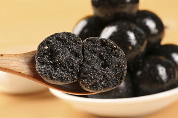 Black sesame balls on wooden spoon with traditional mill - handmade healthy dietary superfood snack