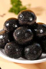 Black sesame nutrition energy balls closeup - healthy pure ground sesame seed pills on white plate