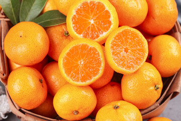 Fresh Organic Oranges and Tangerines in Wicker Basket with Cut Halves Showing Juicy Interior