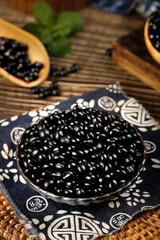 Black Mung Beans and Sesame Seeds in Wooden Bowls on Bamboo Mat with Traditional Asian Cloth