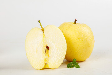 Fresh Golden Yellow Apples Cut in Half Showing White Flesh on White Background