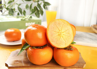 Fresh Fuping Persimmons on Wooden Board - Detailed View of Crisp Orange Fruit Display with Cut Half Showing Interior