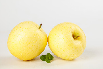 Fototapeta premium Fresh Golden Yellow Apples with Mint Leaves on White Background