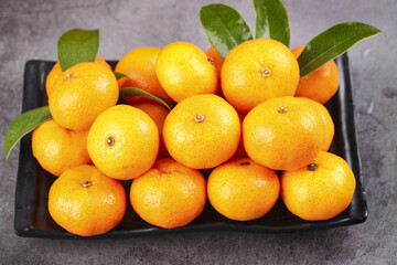 Fresh Guangxi Sihui Honey Tangerines - Sweet Seedless Small Citrus Fruits on Black Tray with Green Leaves