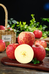 Fresh Red Fuji Apples from Zhaotong China on Rustic Wooden Board with Basket and Herbs
