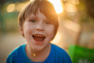 Portrait of a happy 6 year old boy laughing outdoors at sunset. Closeup, shallow DOF.