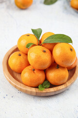 Fresh Organic Oranges with Leaves in Wooden Bowl on White Marble Background