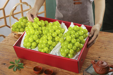 Fresh Green Grapes in Red Gift Box with Tea Set on Wooden Table - Gourmet Fruit Delivery Concept