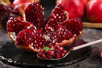 Fresh Pomegranate with Ruby Red Seeds and Arils on Black Slate Surface