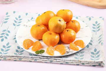 Fresh Mandarin Oranges on Decorative Plate with Peeled Segments and Mint Leaf