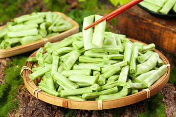 Fresh Green Long Beans in Bamboo Basket with Chopsticks on Wooden Surface