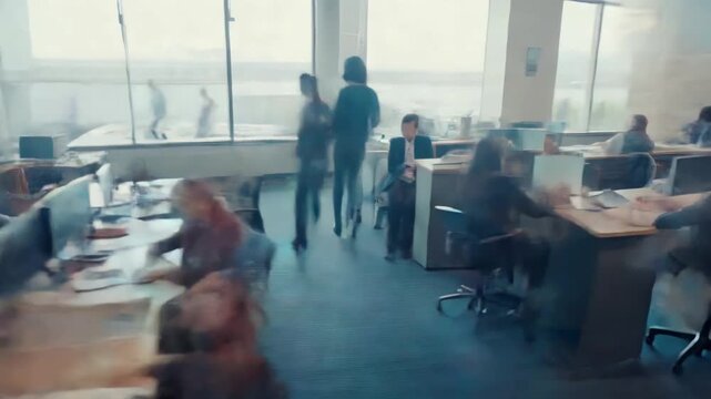 Blurred motion video of a busy office, captured from a high angle, showcasing dynamic activity and modern workspace design.